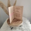 Unutrašnjost drvene čestitke za vjenčanje na preklop s ugraviranim biblijskim citatom o ljubavi i ružičastom vrpcom.